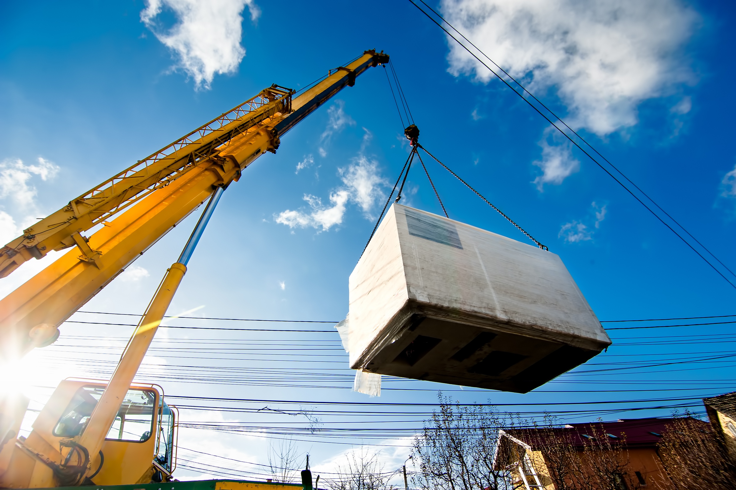 Industrial Crane operating and lifting an electric generator aga Industrial Crane operating and lifting an electric generator against sunlight and blue sky